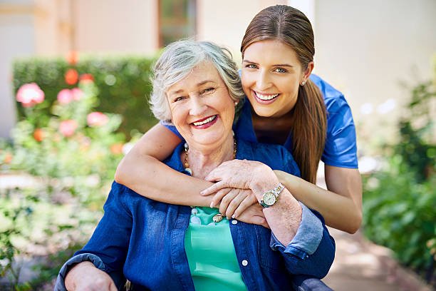 Caregiver warmly assisting an elderly woman at home